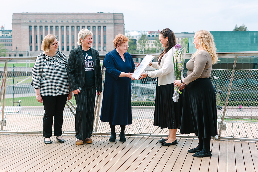 Sanaston edustajat ojentavat kunniakirjan Helsingin kaupunginkirjaston edustajille